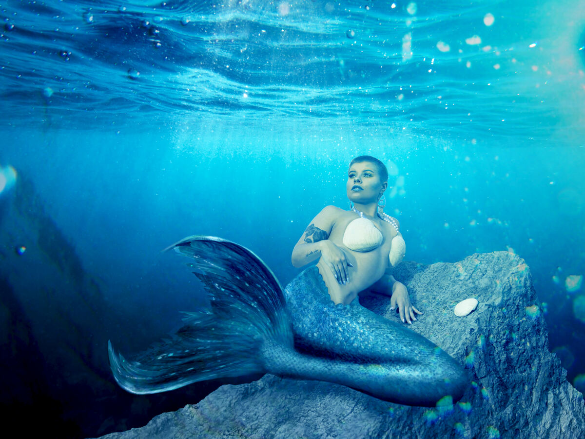 Underwater mermaid portrait on a rocky seabed